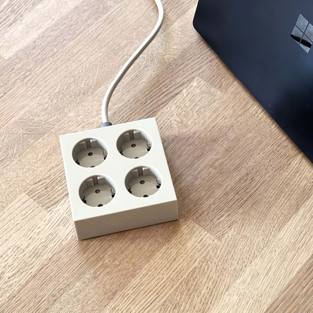 Domusnord Connector beige stikd�se p� et lyst tr�skrivebord ved siden af en b�rbar computer. Den perfekte str�ml�sning og forl�ngerledning til hjemmekontoret.