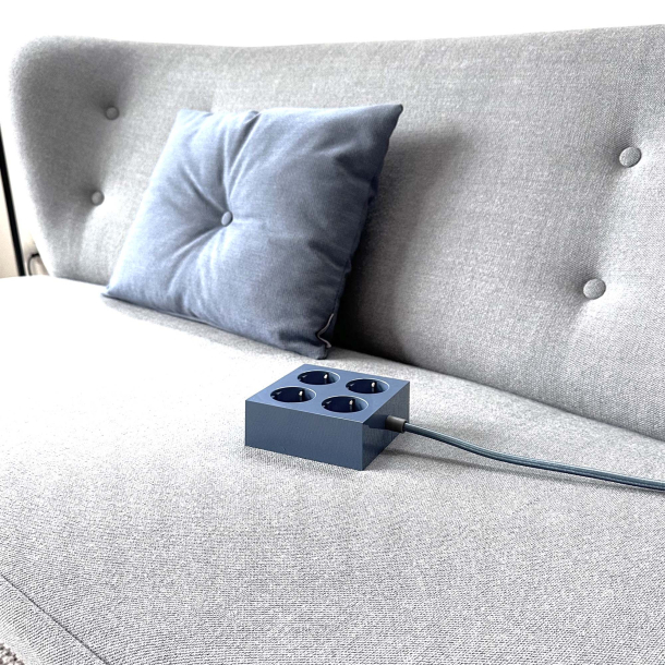 Domusnord Connector stikd�se med 4 stik, stofledning og schuko placeret i en sofa. En elegant forl�ngerledning der g�r det nemt at f� str�m til computer og telefon i sofaen.